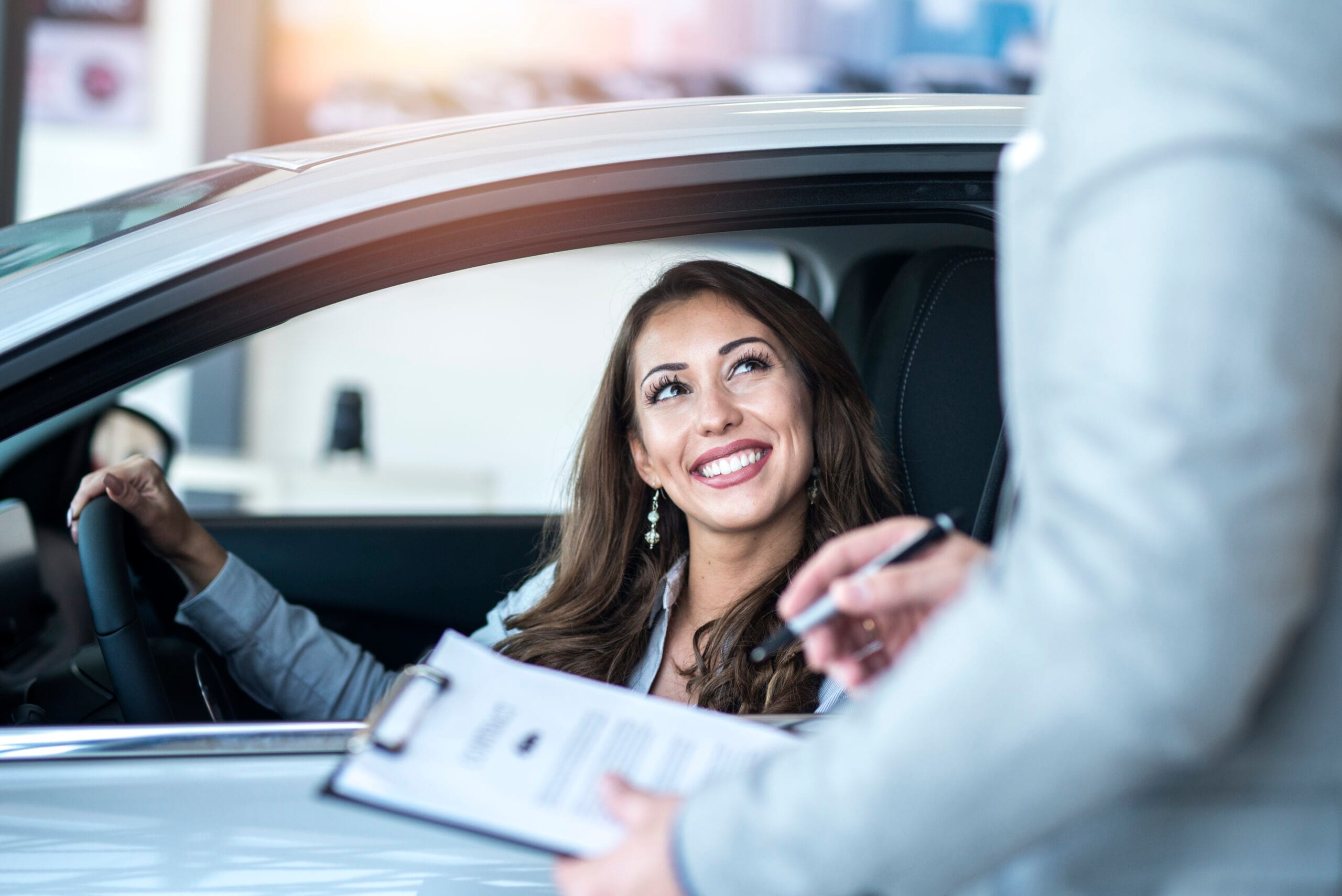 Happy customer buying brand new car at local car dealership.